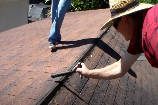 Meridian Roofing worker doing roof inspection using a hammer