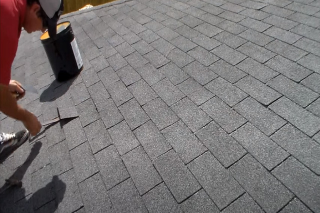 Worker repairing a shingle roof